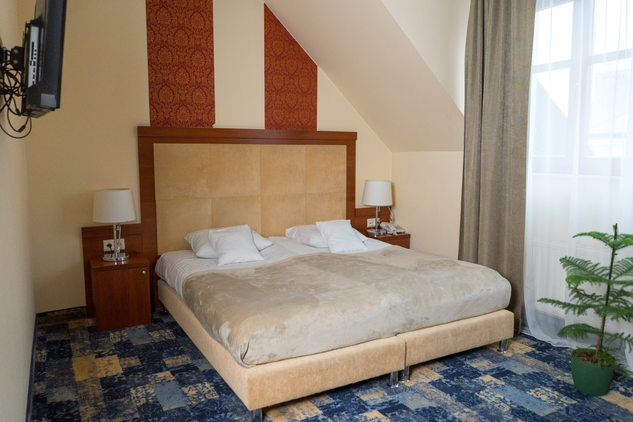 Przytulna sypialnia z dużym łóżkiem, lampkami nocnymi i oknem, idealna na relaksacyjny pobyt.